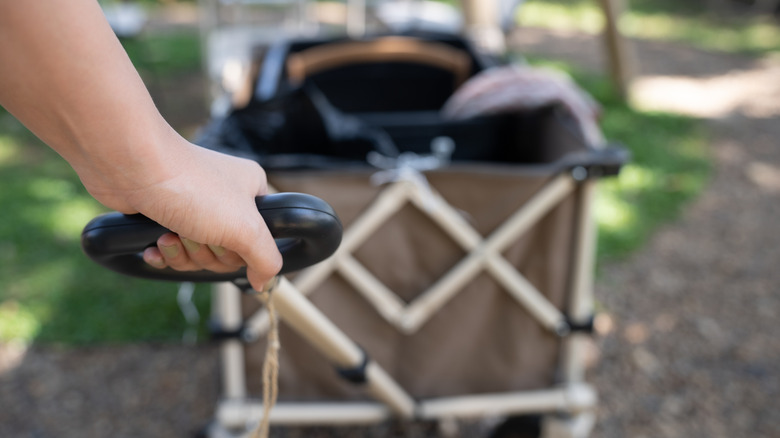 Hand pulling a cart full of camping gear to a walk-in campsite