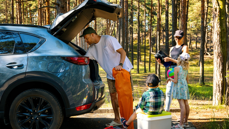 Family removes camping items from trunk of the car