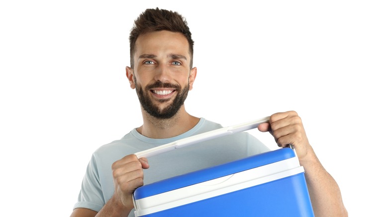 A man holds a small drink cooler