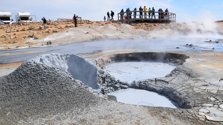 Tourists on a platform looking at a geyser