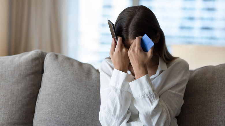 Woman frustrated holding her phone and credit card