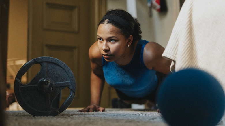 Woman doing push-ups with workout equipment in her room