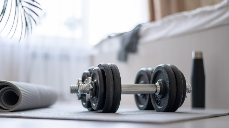 Dumbbells and workout mat in room