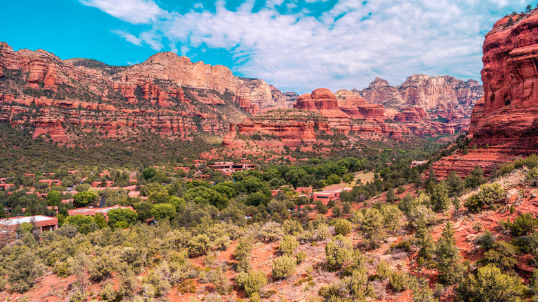 Red cliffs, greenery, and a blue sky