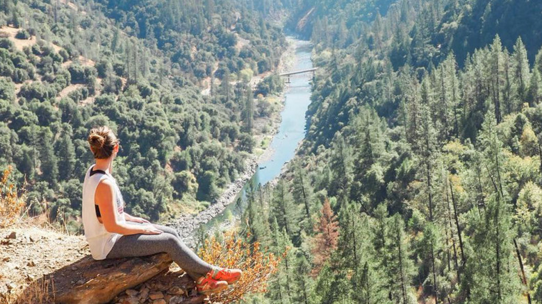 A hiker admires the American River from a rocky perch