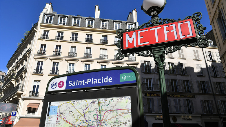 A Metro sign and map in Paris with buildings in the background