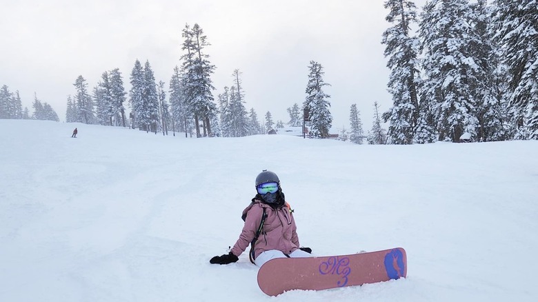 Person in pink jacket sitting down snowy slopes