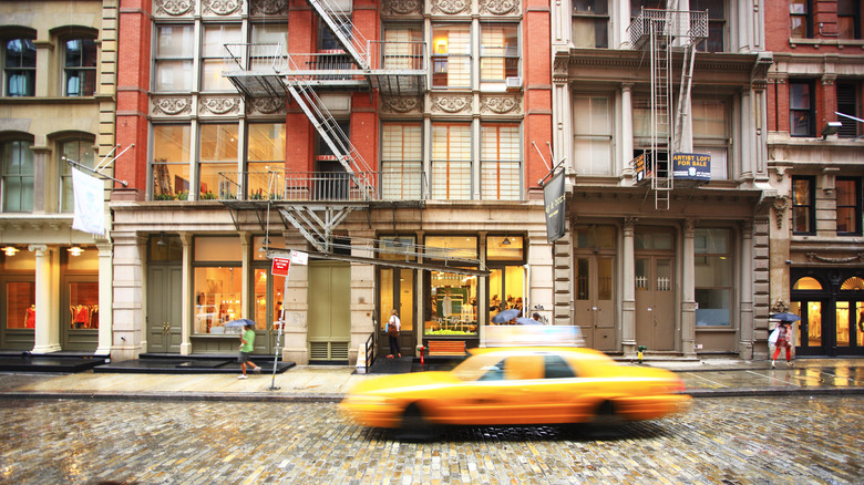 Yellow cab flying down a street in SoHo