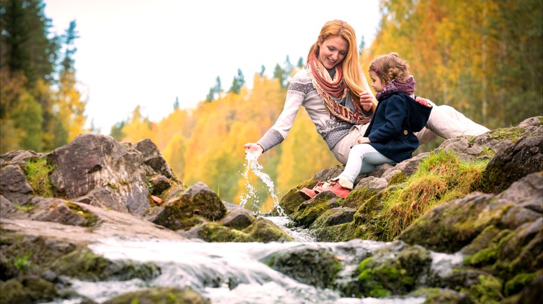 Mom and daughter sitting by creek