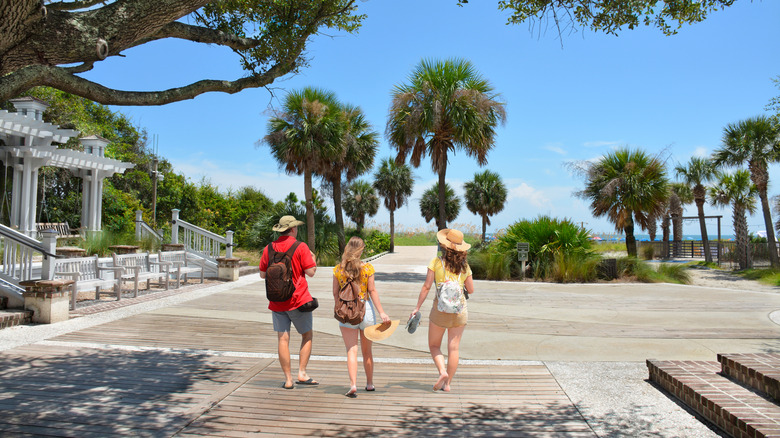 three people walking on wooden boardwalk at Coligny Beach Park