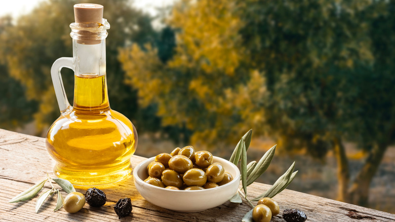 Olive oil in a bottle next to fresh olives