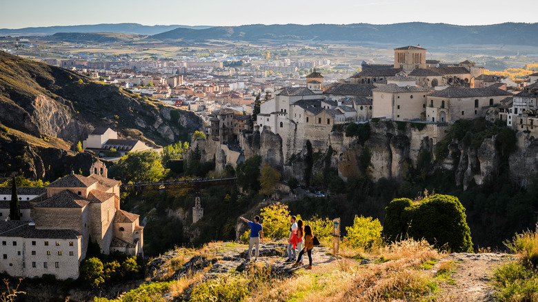 Travelers stand across a crevasse from Cuenca, Spain