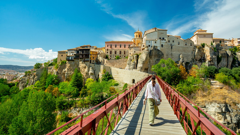 A woman walks across a footbridge toward Cuenca, Spain