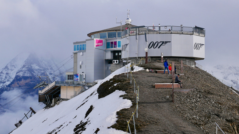 A circular building sits atop a mountain peak in Switzerland