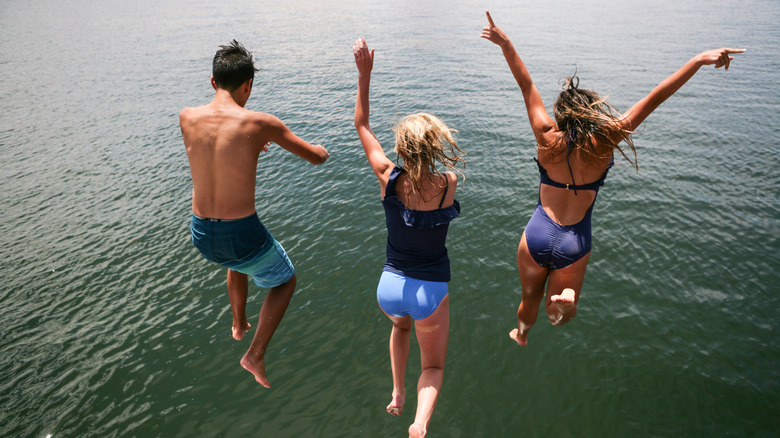 Three teenage friends jumping into lake