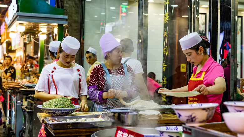 three women making noodles at stall