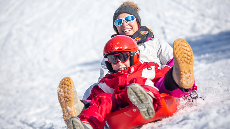 Happy woman and child sled on a snowy hill