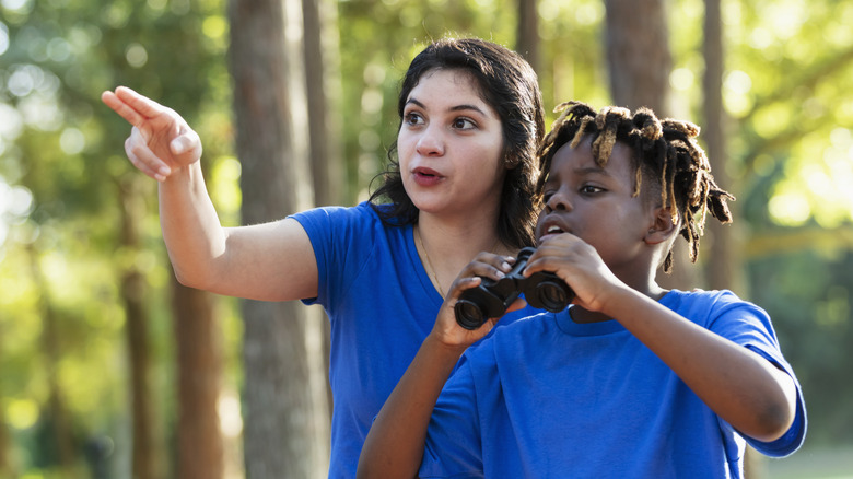 teacher pointing out birds to student with binoculars