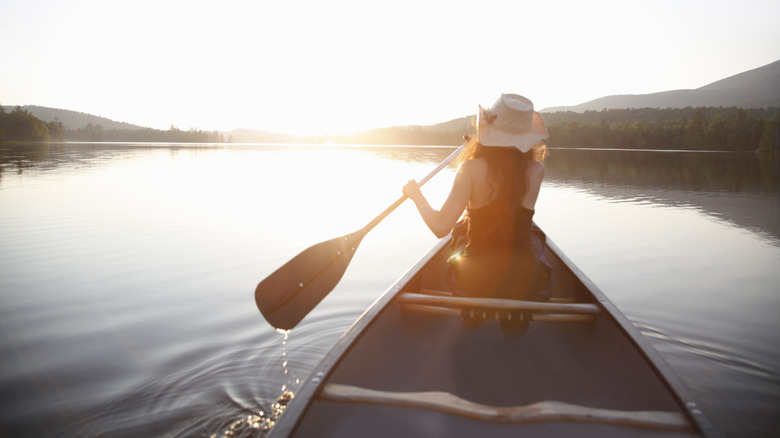 Woman in hat paddling on a lake