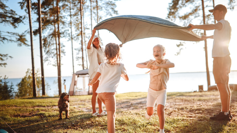 family setting up lakeside campsite