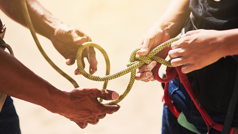 rock climbers tying a knot together before climbing