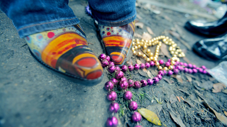 Colorful boots standing next to Mards Gras beads in on the street in New Orleans