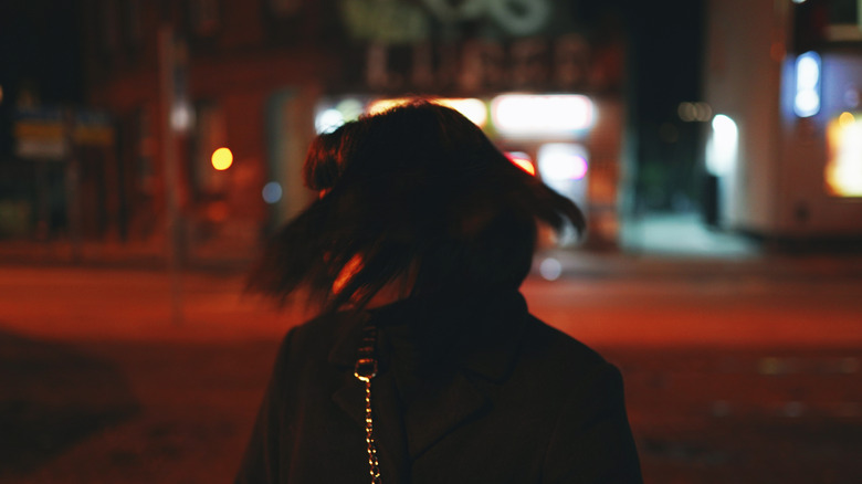 A woman walking alone on a dark city street at night