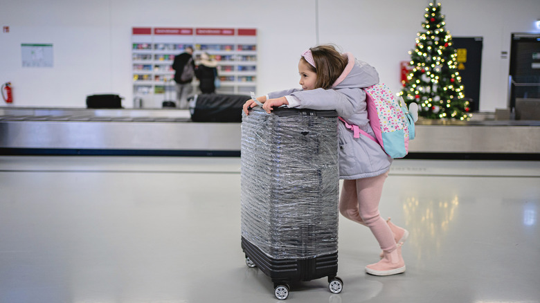 Girl pushing wrapped luggage through airport