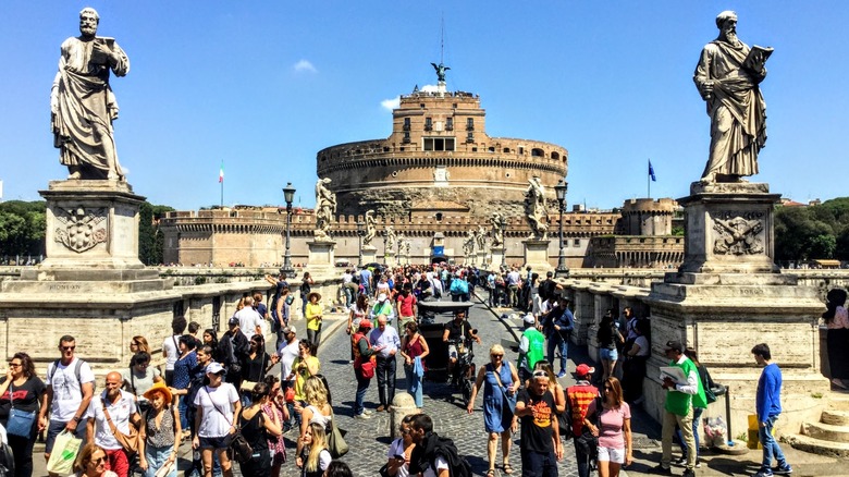 tourists on bridge with statues