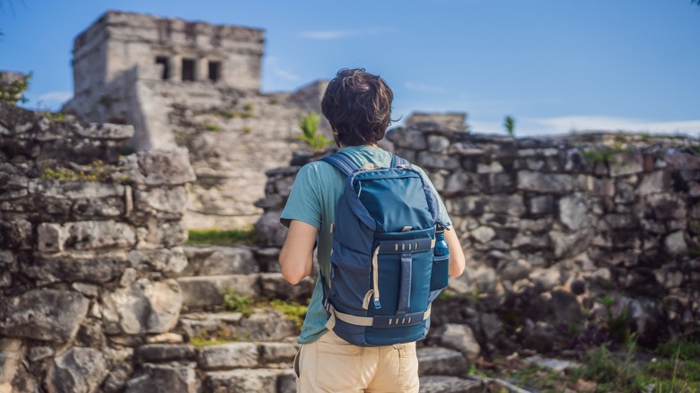 man backpack next to temple ruin
