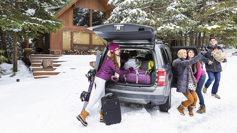 Friends unloading luggage at cabin