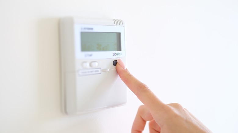 finger pressing wall thermostat