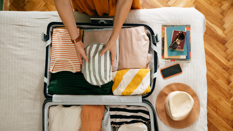 Traveler packing clothes into suitcase
