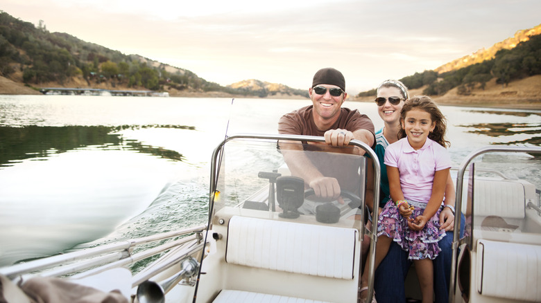 A family cruises along a lake in a power boat