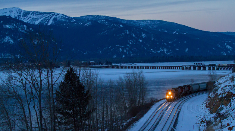 train passing lake in snowy landscape