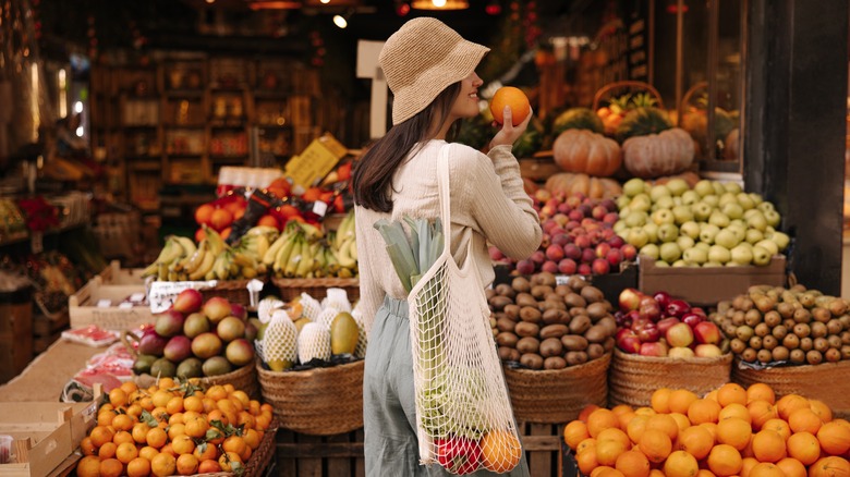 woman sniffing orange at market