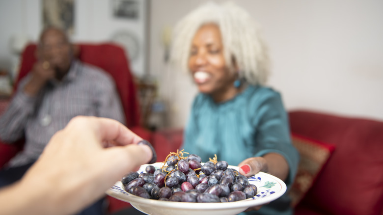 faded background of man with woman offering a hand grapes