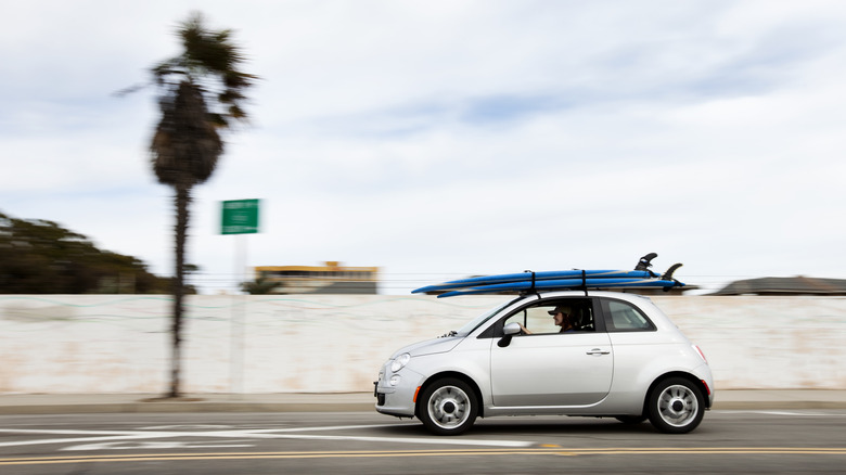 A car carries surfboards down a tropical road