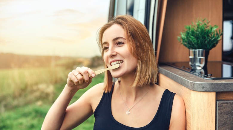 woman brushing teeth outside campervan