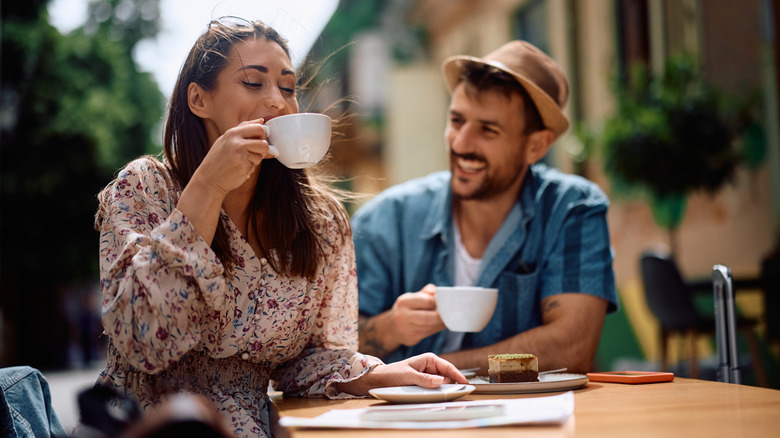 A couple drinking coffee outside.