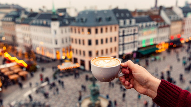 A latte with the view of a European city in the background.