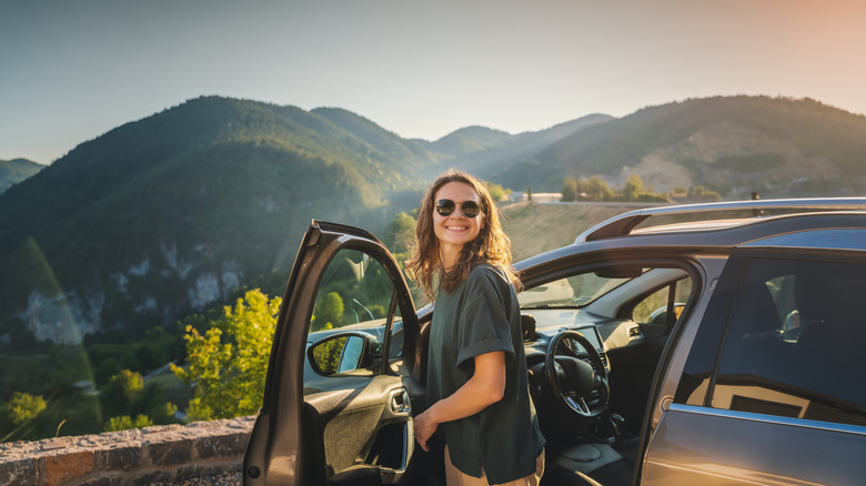 smiling woman standing by car