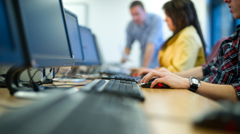 Three people use desktop computers