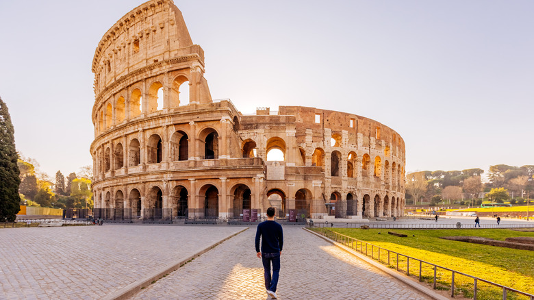 man walking toward Roman ruins