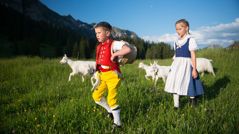 Two Swiss children in a field with goats