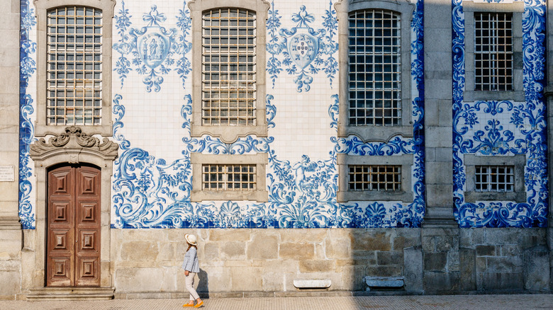 Woman admiring blue-tiled facade of church in Porto