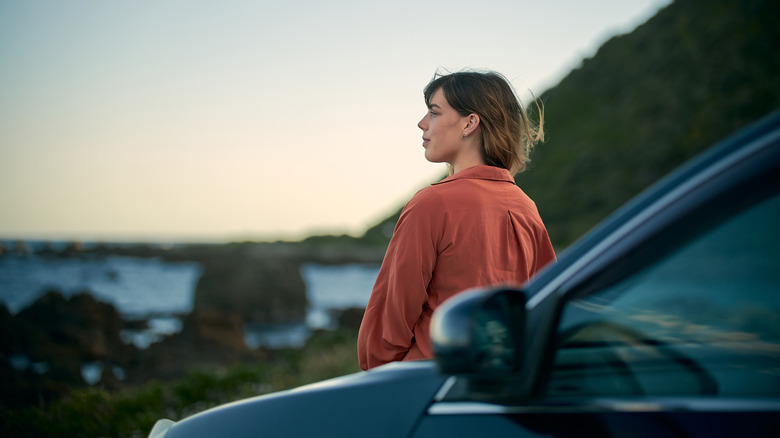 Traveler resting on hood of their car