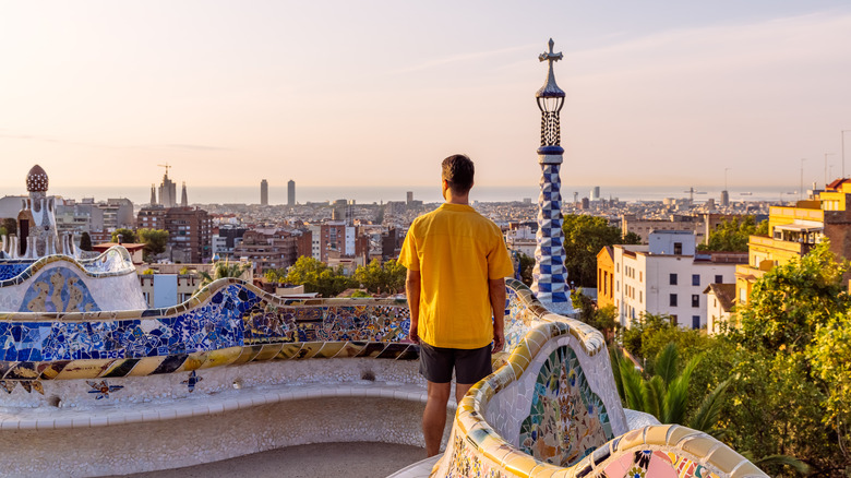 Man in a yellow shirt looking out over a city at sunset