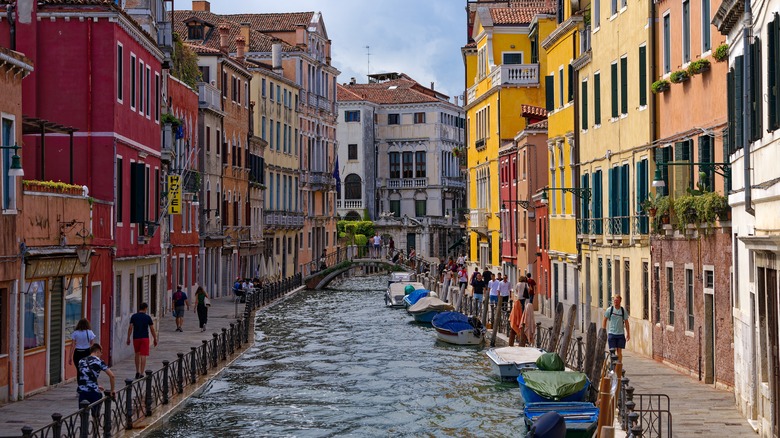 Pedestrians walk on either side of a Venetian canal