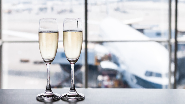 Two glasses of champagne with faded airport scene of airplane on tarmac